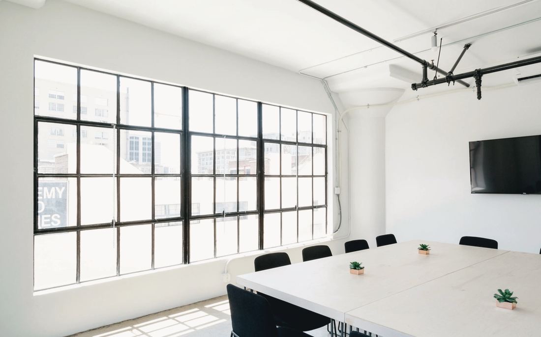 Sala de reuniones vacía con grandes ventanales industriales